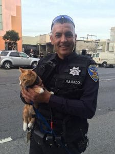 S.F. police Officer Shawn Fulgado holds the cat that helped officers bring a suicidal man down to safety. Photo Courtesy of San Francisco Police Department